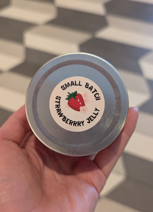 Hand holding a small batch strawberry jelly container with a label.