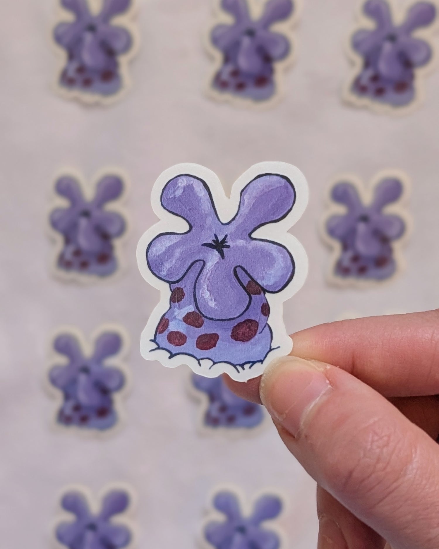 clear purple coral flower sticker held up in front of more out of focus purple coral flower stickers