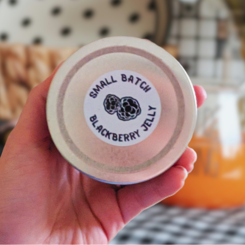 hand holding up 3.30oz NEEDMOREJELLY small batch blackberry jelly 